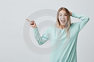 Human face expressions, emotions and feelings. Astonished shocked young blonde female in casual clothes pointing with