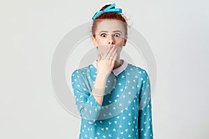 Human face expressions and emotions. Female in despair and shock. The young redhead girl in shoked, looking panic, covered her mou