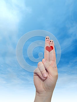 Human or female hands with two fingers painted with a red heart and smiley faces