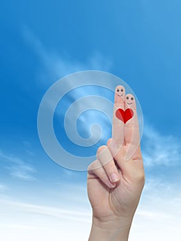 Human or female hands with two fingers painted with a red heart and smiley faces