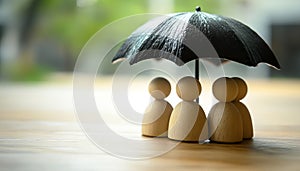 Human figures under umbrella on light wooden table. Insurance concept
