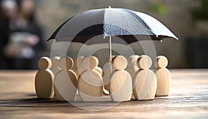 Human figures under umbrella on light wooden table. Insurance concept