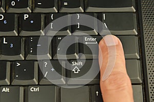 Human finger press enter button on computer notebook keyboard