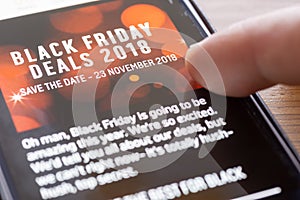 Human finger thumb over Black Friday Deals 2018 text on shopping app on smartphone screen closeup