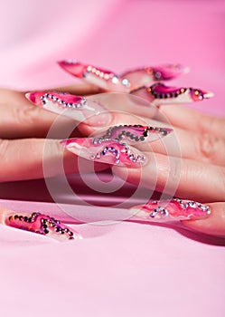 Human fingers with long fingernail over pink