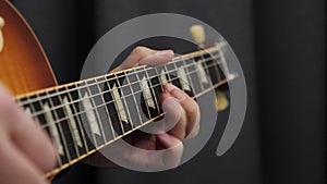 Human fingers playing on guitar. Close up of guitar fretboard and male hand playing chords. Professional guitar solo. Music lesson