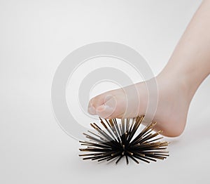 Human foot massage therapy with help of artificial sea urchins model on grey