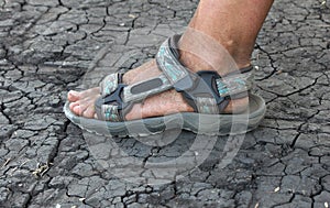 Human foot in sandals on the cracked earth