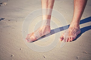 Human foot walking on white sand beach