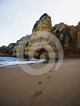 Human footprints steps on pictureque sand beach Praia de Dona Ana atlantic ocean in Lagos Algarve Portugal Europe