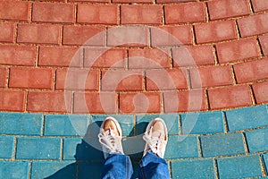 Human foots in shoes standing on the pavement tiles