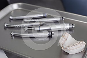 Human gypsum jaw and dental handpieces on tray