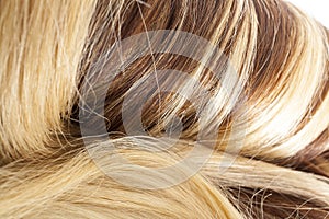 Human hair european hair weft for hair extension. Brown blonde hair texture closeup pattern.