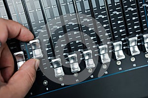 Human hand adjusting buttons on audio mixer