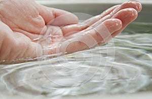 Human hand bailing water in stainless basin