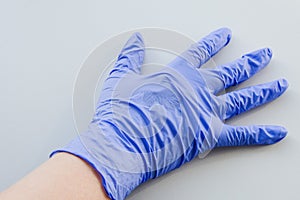 Human hand in blue latex glove, personal protective equipment medical accessory to ensure the safety of staff and patient. To