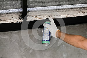 Human hand are caulking roof leaks with canned caulk foam