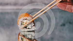 Human Hand With Chopsticks Hold and Take Away One Sushi Roll, Close-Up