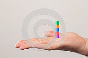 Human hand with colourful bricks over a white wall