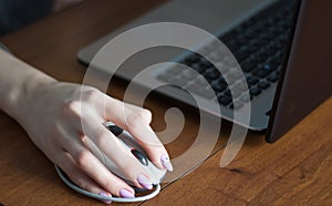 Human hand on computer mouse. Laptop on desk.