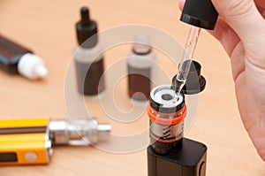 Human hand filling e-liquid in vaping atomizer
