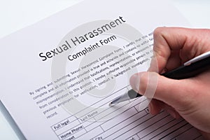 Human Hand Filling Sexual Harassment Complaint Form photo