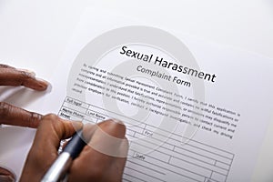 Human Hand Filling Sexual Harassment Complaint Form With Pen photo