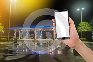Human hand hold smartphone, tablet, cell phone with blank screen on blurry filling station background.