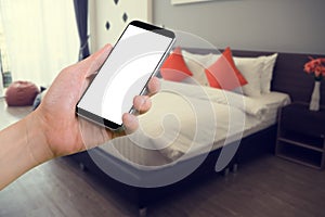 human hand hold smartphone, tablet, cell phone with blurry modern bedroom.