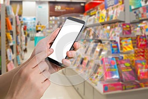 Human hand hold and touch blank screen smart phone, tablet, cellphone on blurry bookshelf in bookstore