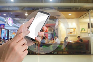 Human hand hold and touch smartphone with blank screen on blurred people eating at food court background.
