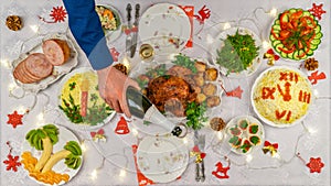 Human hand holding bottle of champagne and pouring sparkling wine into glass against festive served Christmas table. Dinner for