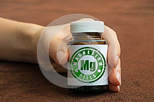 Human hand holding a bottle of pills with magnesium photo