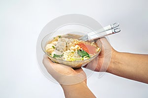 A human hand holding a bowl with a meatball (bakso) photo