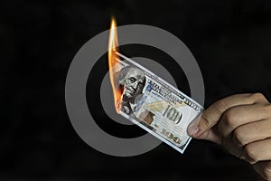 Human hand holding burning 100 dollar bill. concept of inflation decrease in the purchase of foreign currency, and devolution