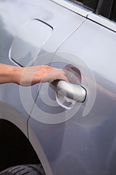 Human hand holding car door handle