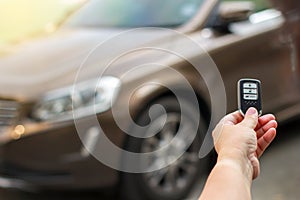 Human hand holding the car remote control against blur car