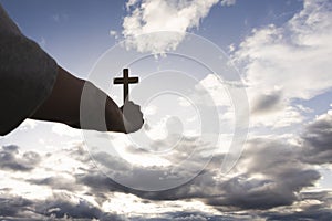 Human hand holding a cross up in the sky. symbol of faith in god Prayer. Deliverance. Prayer. Christian concept