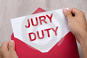 Human Hand Holding Jury Duty Document In Envelope