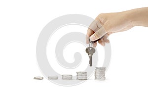 Human hand holding a key on stack of coins