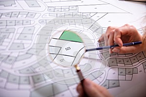 Human Hand Holding Magnifying Glass Over Cadastre Map