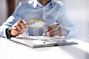 Human Hand Holding Magnifying Glass Over Invoice