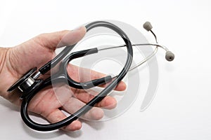 A human hand holding a medical doctor`s stethoscope which features a white background.