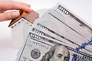 Human hand holding a model house by the side of aAmerican dolla