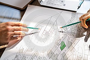 Human Hand Holding Pencil Over Cadastre Map photo