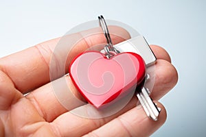 Human Hand Holding Red Heart Shape Key Chain With Key