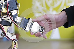Human hand holding a robot hand with a handshake