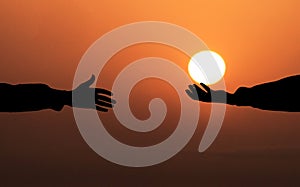 Human hand holding the Sun and giving it To another person. Helping hand Concept. Sunset Sun background. God`s salvation