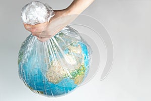 The human hand holds the earth in captivity. Globe in a white plastic bag. The concept of environmental disaster on a white