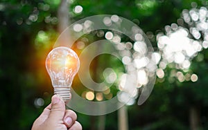 Human hand holds a light bulb with natural bokeh background. Idea, innovation and inspiration concept, creative concept, earth